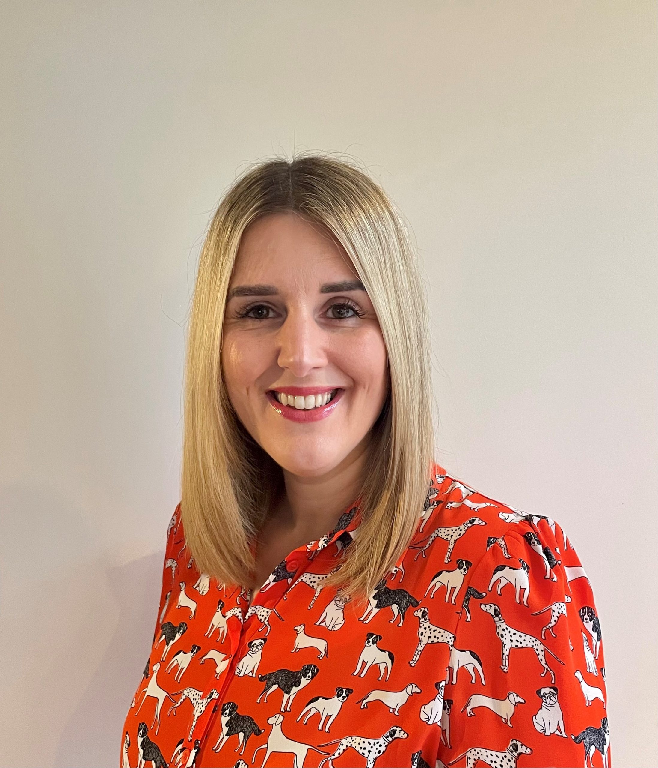 Helen smiles at the camera with an orange blouse