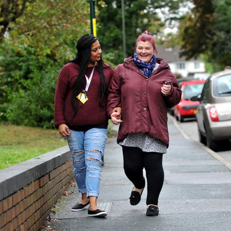 Photo of carer and individual walking down street