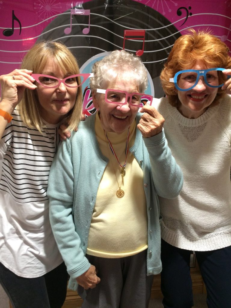 three women wearing large glasses smiling at the camera